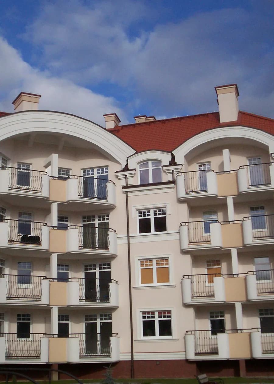 Blok z lat dwutysięcznych na osiedlu Belweder w Olsztynie: czerwony dach, balkony z kutymi balustradami